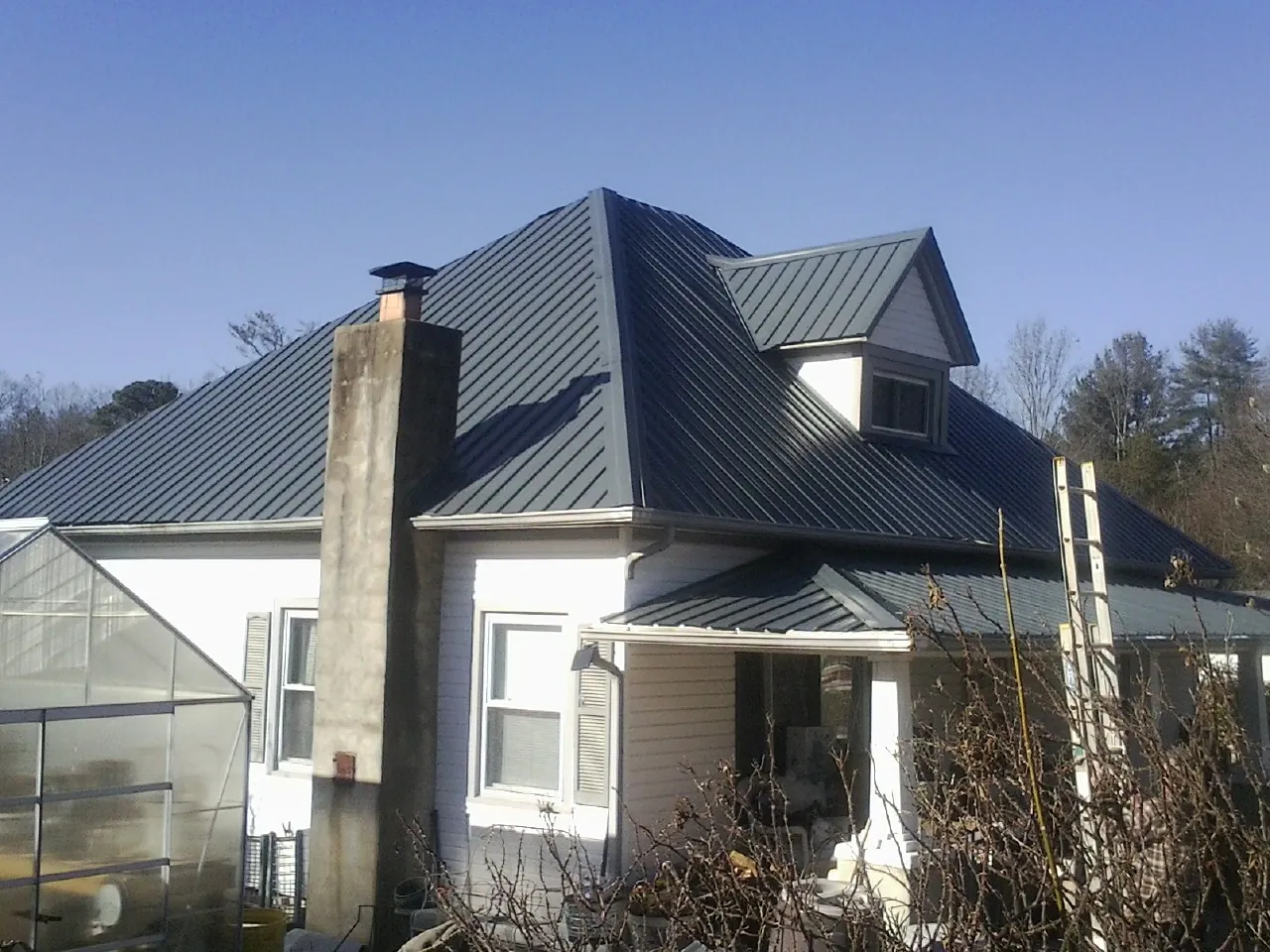 Dark blue standing seam metal roof on a white farmhouse with dormer — Slate & Tile Roof Repair by Roofing Brothers in Fullerton