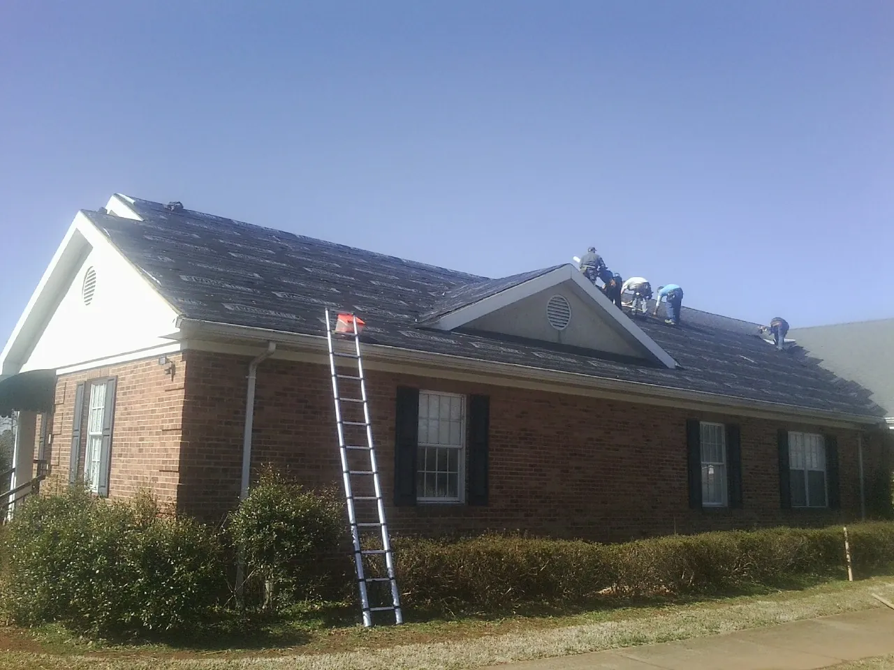 Crew tearing shingles off a brick ranch roof with a ladder set — Metal Roof Repair work by our crew in Fullerton