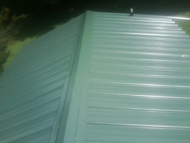 New green metal panels meeting at the ridge of a roof — Flat Roof Repair work by our crew in Fullerton