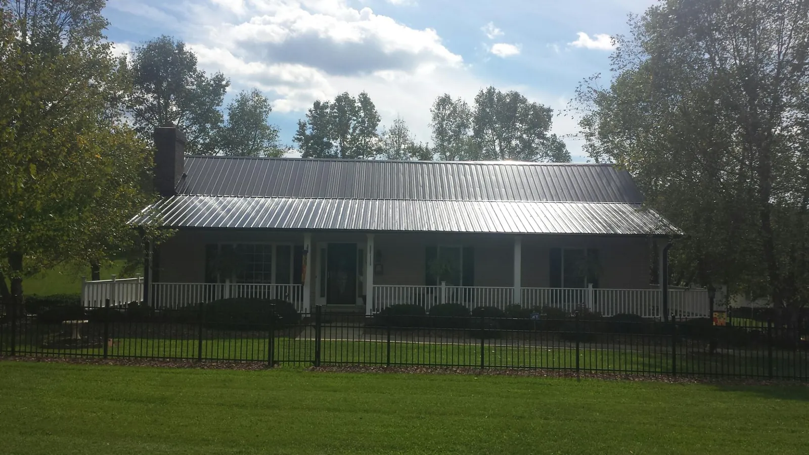 Gray metal roof on a brick ranch with a full width front porch — Gutter Guard Installation work by our crew in Fullerton